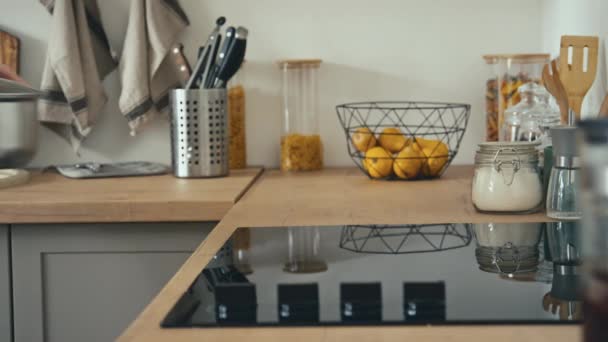 Boczne ujęcie nierozpoznawalnego mężczyzny zakładającego garnek na kuchenkę elektryczną i podgrzewającego go w nowoczesnej kuchni domowej - Materiał filmowy, wideo