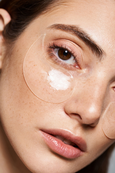 A young Caucasian woman with under eye patches exuding a serene beauty routine, close up - 写真・画像