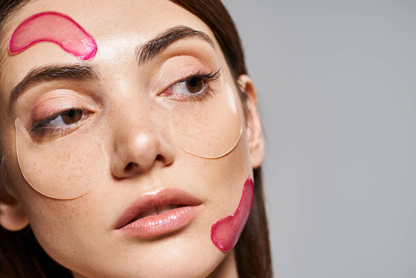 A young Caucasian woman with brunette hair and clean skin wearing pink moisturizing patches on face - Photo, Image