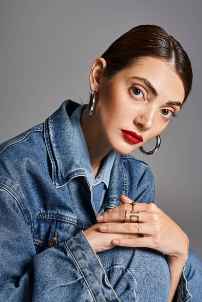 A young Caucasian woman with brunette hair in a stylish jean jacket and bold red lipstick. - Photo, Image