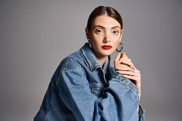 A young Caucasian woman with brunette hair in a stylish jean jacket and bold red lipstick. - Photo, Image