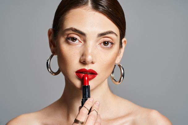 A young Caucasian woman with brunette hair holds a lipstick in her hand, showcasing beauty and elegance. - Photo, Image