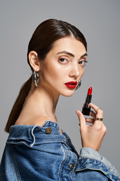 A young Caucasian woman with brunette hair holds a lipstick in her hand, exuding elegance and beauty. - Photo, Image
