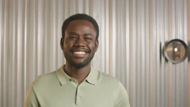 Zoom σε πορτρέτο του χαρούμενου Αφροαμερικανού που κοιτάζει την κάμερα και χαμογελά χαρούμενα στο κουρείο - Πλάνα, βίντεο