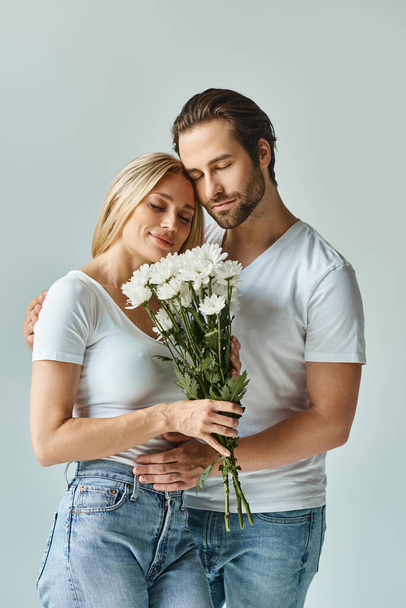 Un momento romántico capturado como una mujer tiernamente sostiene un ramo de flores junto a un hombre, exudando amor y conexión. - Foto, imagen