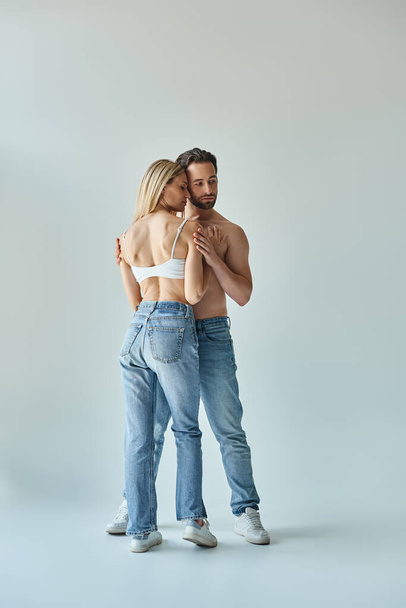 A man and a woman wearing jeans embrace each other in a romantic and intimate moment. - Photo, image