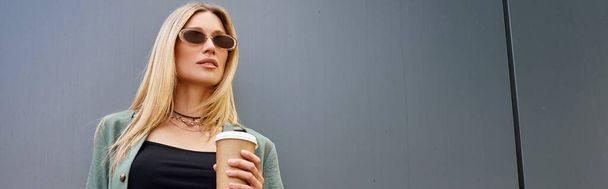 Женщина, наполненная теплом, держит чашку кофе в руке, олицетворяя комфорт и спокойствие.. - Фото, изображение