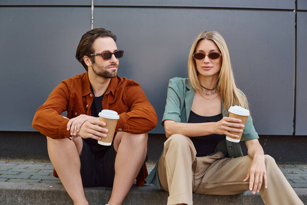 Ein Mann und eine Frau sitzen eng beieinander, halten Kaffeetassen und teilen einen Moment der Intimität und Verbundenheit. - Foto, Bild