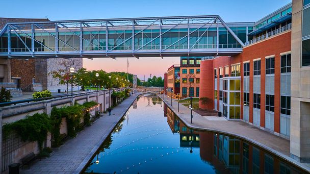Paesaggio urbano crepuscolare con moderno ponte pedonale sul canale riflettente a Indianapolis, 2023 - Foto, immagini