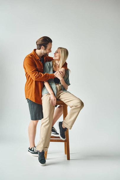 Ένας άντρας και μια γυναίκα, αποπνέουν ρομαντισμό, κάθονται κοντά σε μια καρέκλα.. - Φωτογραφία, εικόνα