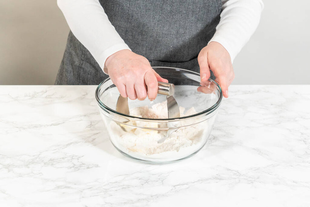 Mezclar ingredientes secos con un batidor de mano en un tazón de vidrio para hornear cupcakes de canela sin levadura. - Foto, Imagen