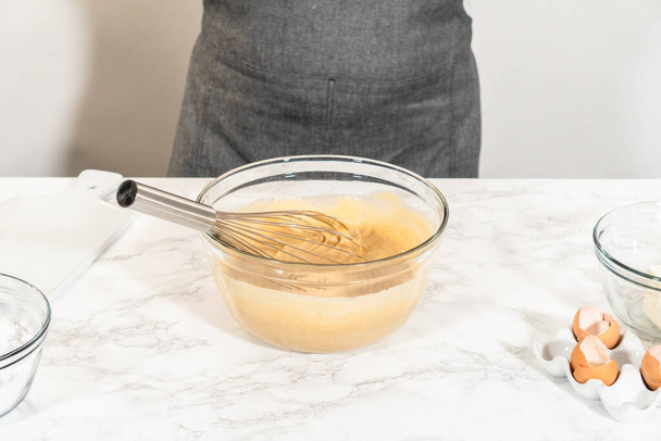 Dans un grand bol en verre, les ingrédients sont savamment mélangés pour créer la pâte pour la cuisson du délicieux gâteau Bundt aux carottes. - Photo, image