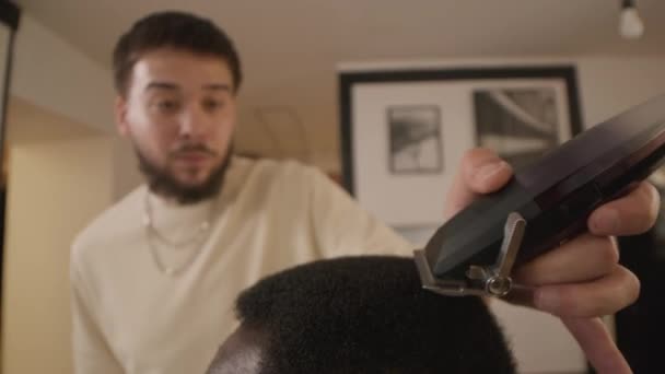 Gros plan prise de vue sélective de coupe coiffeur cheveux du client masculin avec tondeuses tout en travaillant dans le salon de coiffure - Séquence, vidéo