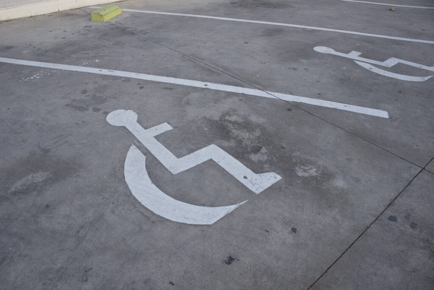 Auf dem Boden lackierter Rollstuhl signalisiert, dass es einen Behindertenparkplatz gibt - Foto, Bild