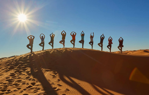 Група туристів захоплює радісні моменти, вражаючи грайливі пози, затінені на тлі зачаровування пустелі Сахари. Марокко. - Фото, зображення