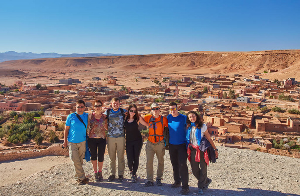 Tourists capture a shared moment, smiling and posing for a group photo against the historic backdrop of Ait-Ben-Haddou's ancient architecture - Photo, Image