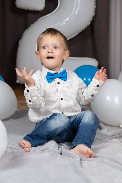 Маленький блондинка з блакитними очима відзначає свій день народження серед надувних кульок - Фото, зображення