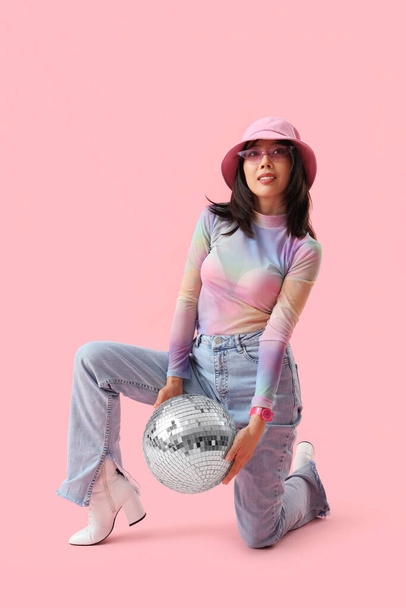 Модная красивая молодая азиатка с диско-мячом на розовом фоне - Фото, изображение