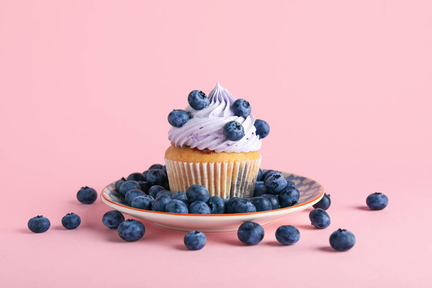 Plate of tasty cupcake with blueberries on pink background - Photo, Image