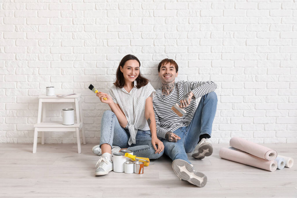 Giovane coppia con pennelli durante la riparazione nella loro nuova casa - Foto, immagini
