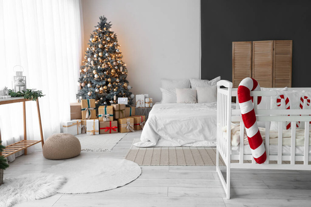 Интерьер светлой спальни с детской кроваткой и елкой - Фото, изображение