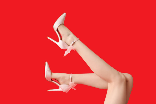 Pernas de bela jovem mulher em saltos altos bonitos no fundo vermelho - Foto, Imagem
