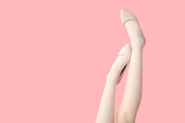 Ноги красивой молодой женщины на стильных каблуках на розовом фоне - Фото, изображение