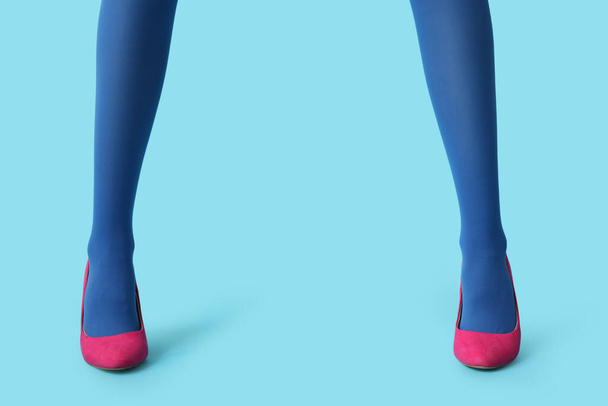 Pernas de bela jovem mulher em saltos altos elegantes no fundo azul - Foto, Imagem
