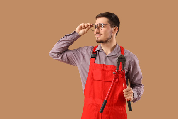 Nuori miespuolinen työntekijä silmälaseissa pulttileikkurilla beige taustalla - Valokuva, kuva