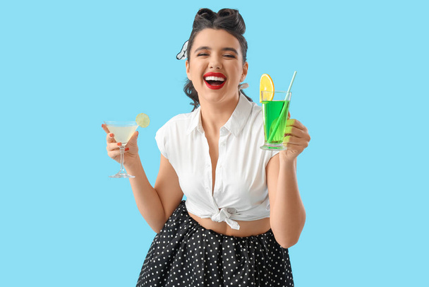 Attraktive Pin-up-Frau mit Cocktails auf blauem Hintergrund - Foto, Bild