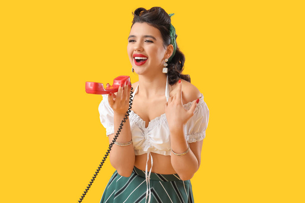 Приваблива жінка, що розмовляє по телефону на жовтому тлі - Фото, зображення