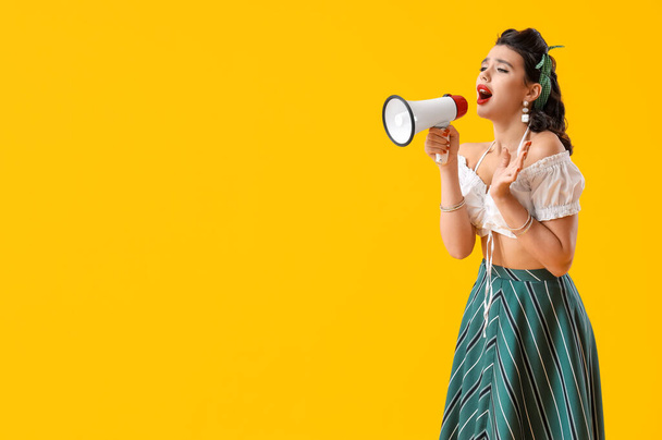 Atrakcyjny pin-up kobieta krzyczy do megafonu na żółtym tle - Zdjęcie, obraz