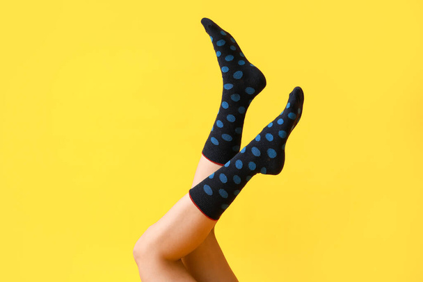 Sarı arka planda siyah noktalı çoraplı genç kadın bacakları. - Fotoğraf, Görsel