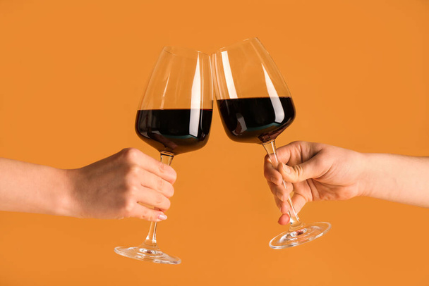 Mains féminines avec verres de vin rouge sur fond orange - Photo, image