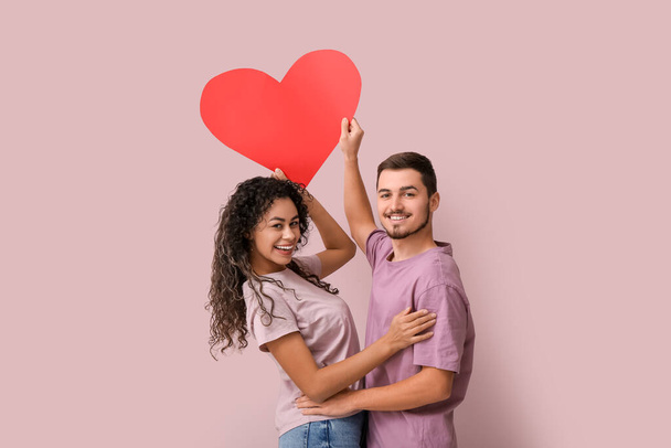 Mladý pár s červeným srdcem na Valentýna na růžovém pozadí - Fotografie, Obrázek