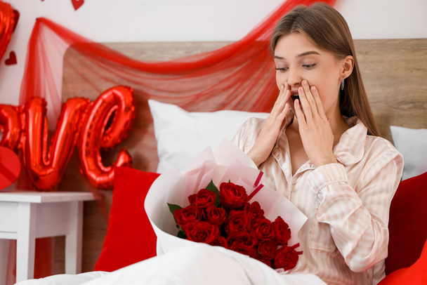 Giovane donna sorpresa con rose che giace in camera da letto a San Valentino - Foto, immagini