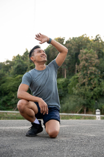 Ein Porträt eines gutaussehenden, glücklichen asiatischen Mannes in Sportbekleidung, der im Freien trainiert. Hobby und gesunde Lebensstilkonzepte - Foto, Bild