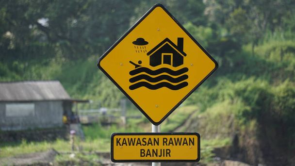 Signo amarillo con fondo natural. Kawasan rawan banjir significa zona propensa a inundaciones - Foto, imagen