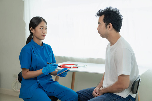 An Asian male patient consults a female doctor at the hospital. Concept of annual health check-up service for male patients - Photo, Image