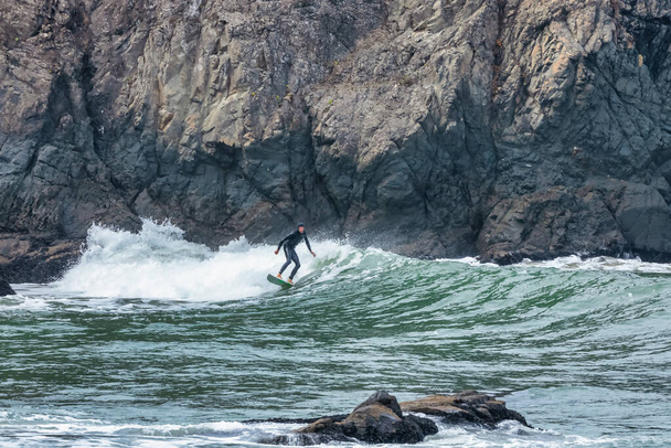 カリフォルニア州サンフランシスコ - 2021年10月23日 - サンフランシスコの背景にある崖でサーファーが波に乗る - 写真・画像