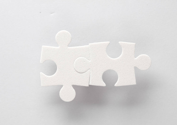Weiße Puzzleteile auf grauem Hintergrund. - Foto, Bild