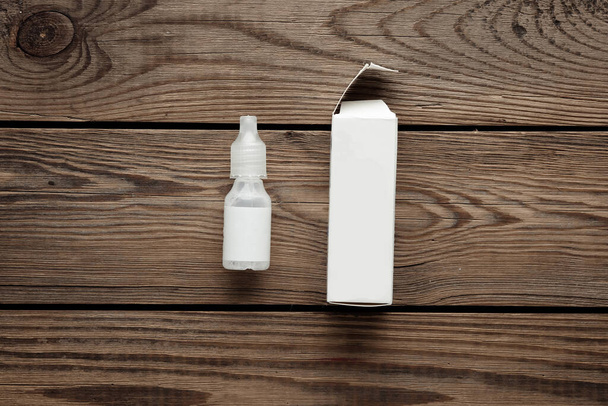 Botella de gotas para los ojos con embalaje en una mesa de madera. Plantilla para diseño - Foto, Imagen