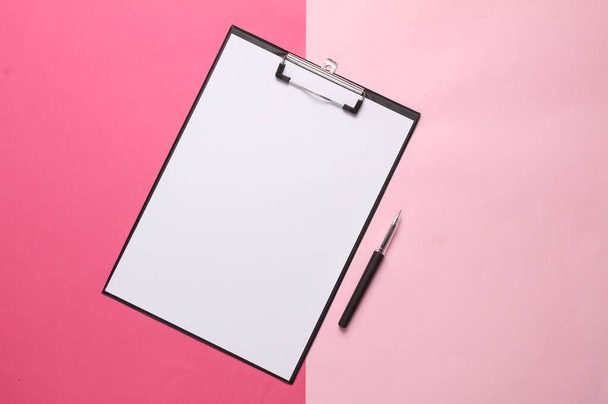 Кліпборд з порожнім аркушем паперу і ручкою на рожевому фоні - Фото, зображення