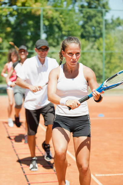 Grupo energético que participa en una sesión de entrenamiento de tenis cardiovascular de alta energía, combinando habilidades de fitness y tenis - Foto, imagen