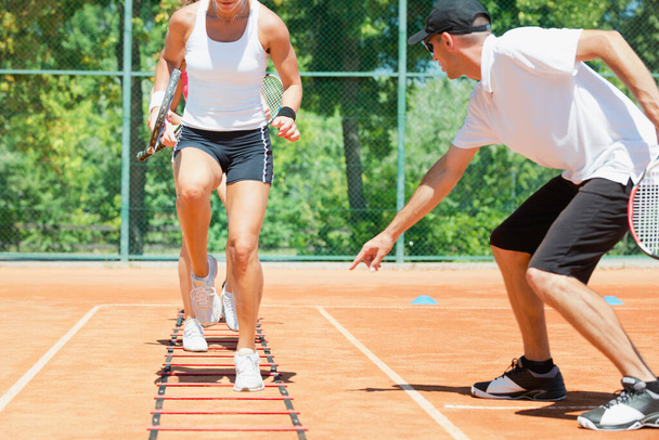 Groupe énergique participant à une séance d'entraînement de cardio-tennis à haute énergie, combinant fitness et tennis - Photo, image