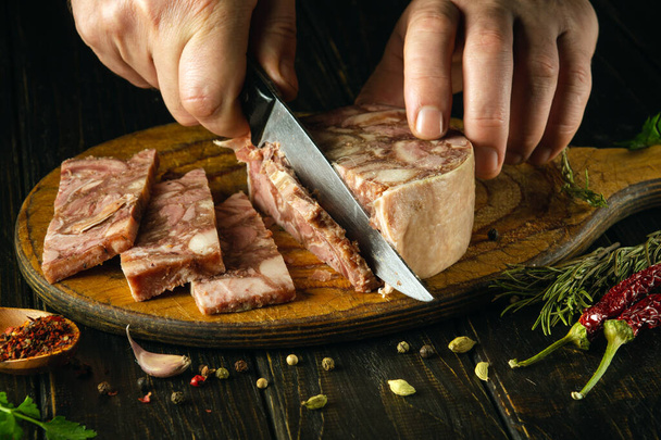 Kokki leikkaa lihaksen veitsellä keittiön pöydälle ennen voileipien valmistamista. Idea herkulliseen välipalaan, jossa on pääjuustoa ja aromaattisia mausteita - Valokuva, kuva
