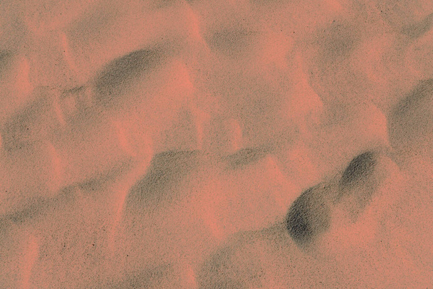Fondo naranja rosado hecho de textura de arena ondulada del desierto. Arena de playa fina. Color del año 2024 - Melocotón Fuzz. - Foto, imagen