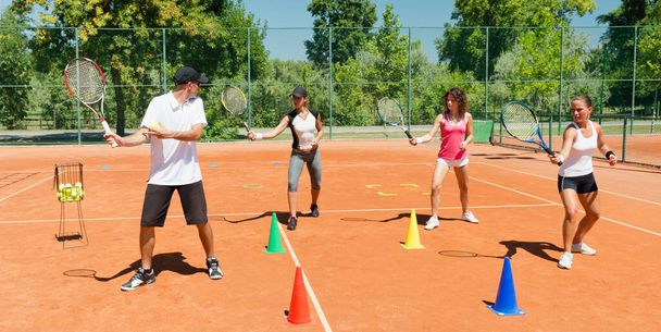 Energetická skupina účastnící se vysoce energetického tréninku kardio tenisu, kombinující fitness a tenisové dovednosti - Fotografie, Obrázek