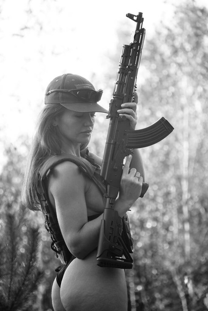 zwart-wit foto van een half naakt soldaat meisje in het bos - Foto, afbeelding