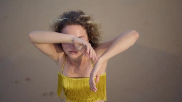 Confident χορεύτρια κινείται το σώμα εκτελεί σύγχρονο στυλ στο φως του ήλιου βράδυ closeup. Top view χαλαρή γυναίκα χορεύει αισθησιακά με τα χέρια. Σγουρή γυναίκα performer δείχνει χορό αυτοσχεδιασμό στην παραλία - Πλάνα, βίντεο